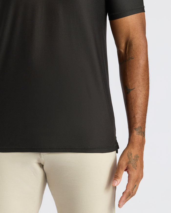 Black Active Polo 2.0 worn tucked into beige trousers.