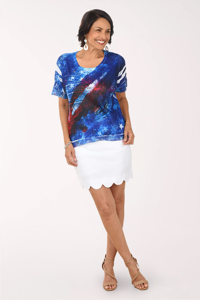 Woman wearing a colorful abstract design shirt with a white skirt on a white background