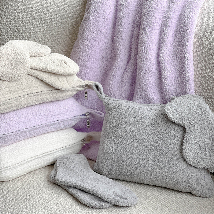 Soft lavender, cream, and gray chenille travel blankets and matching eye masks paired with cozy socks, showcasing the Travel Blankets - Solid - Chenilla Fine™ | Kashwére collection.