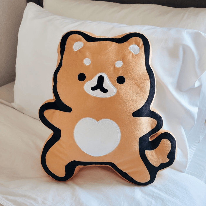 Plush cushion featuring a cute cartoon fox with a heart-shaped patch on its belly, soft orange and black fabric, named Warrior Fox Plushie | Lucky Owl, resting on a white bed.