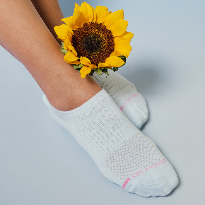 White liner compression socks with a textured design, positioned near a sunflower on a light blue background.