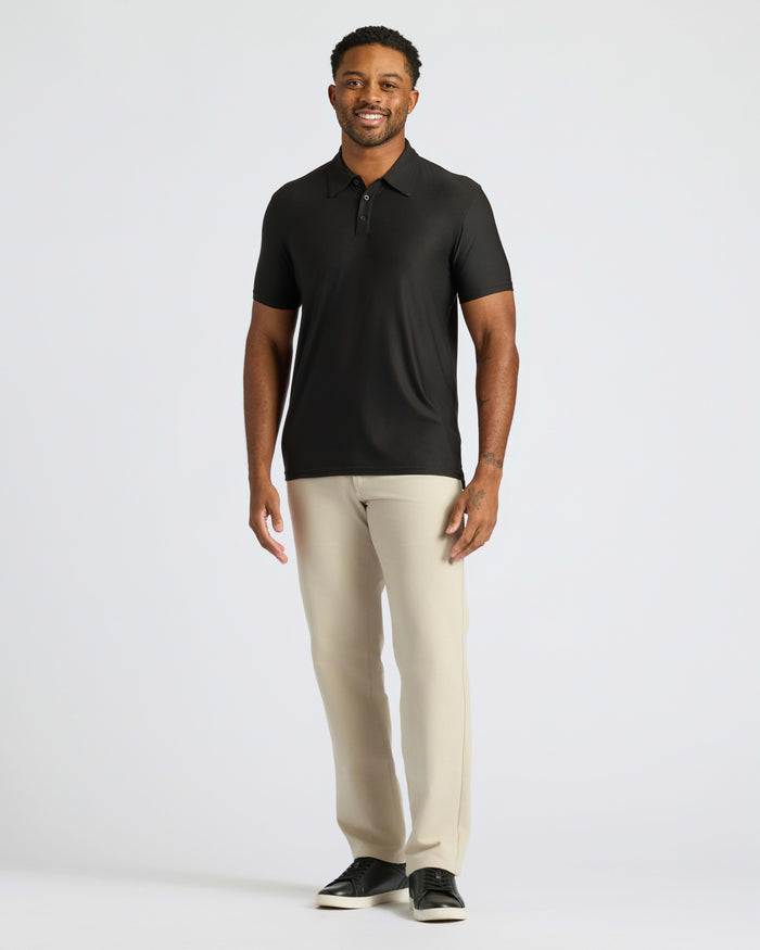 Man models Black Active Polo 2.0 with beige trousers and black sneakers.
