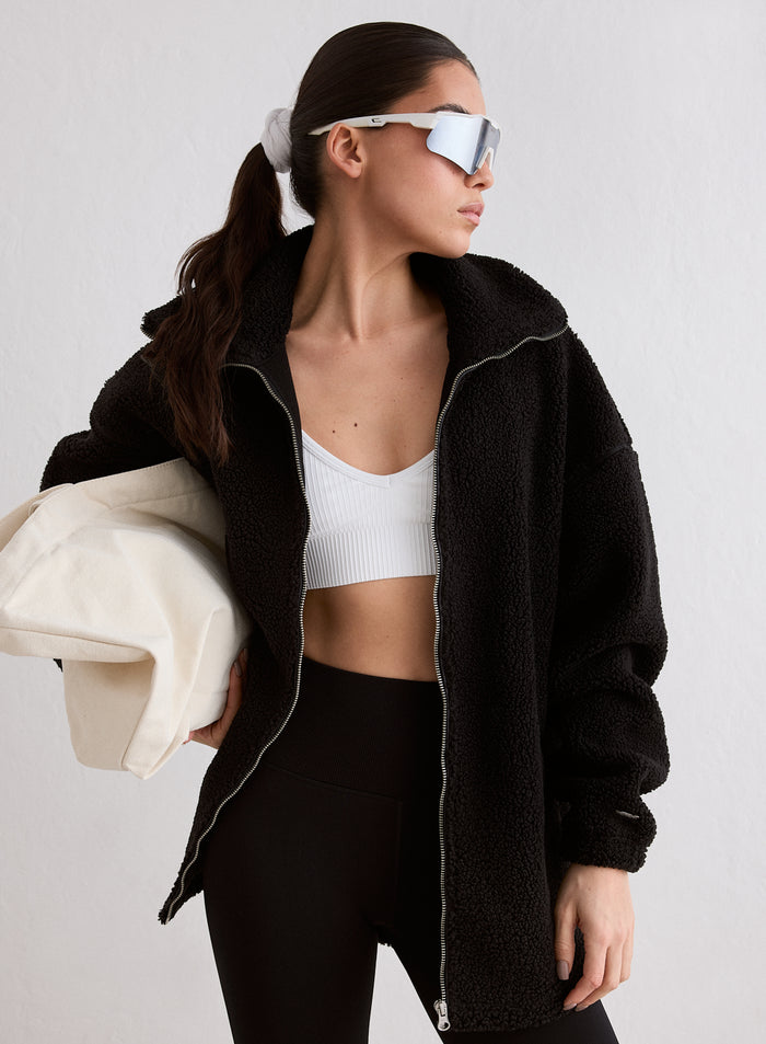 A woman wearing a black oversized Pile Jacket with a high collar and zip detail, paired with a white crop top and black leggings [M-174cm]