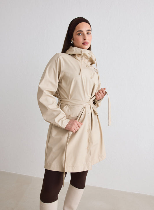 A model wearing a Cafe Au Lait Rain Jacket from aim'n with a tied waist belt and hood [M-174cm]