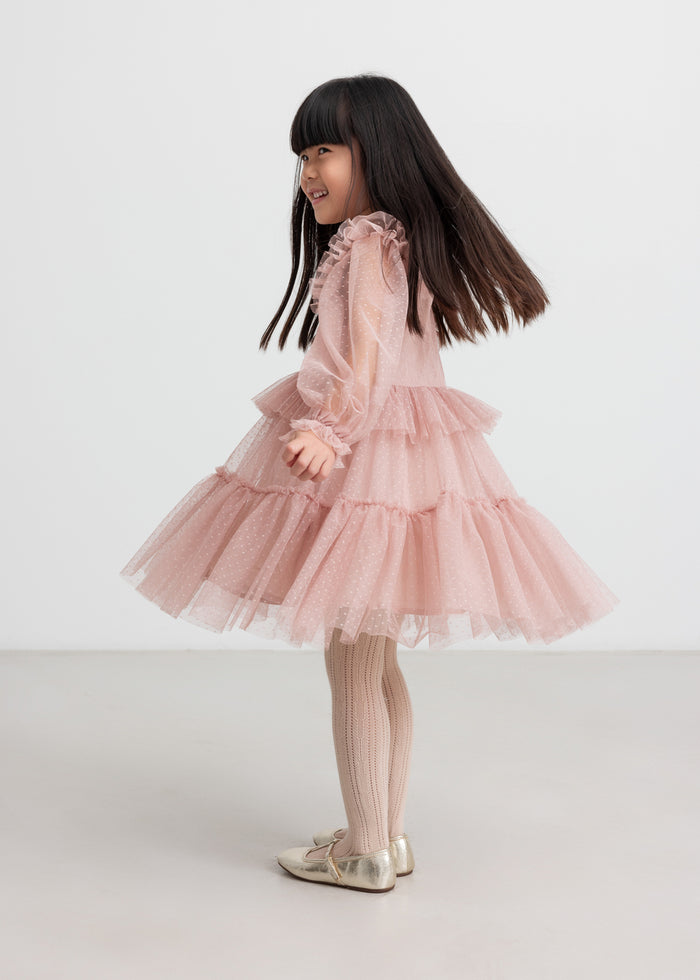 Child wearing pink tulle dress with ruffles on the sleeves
