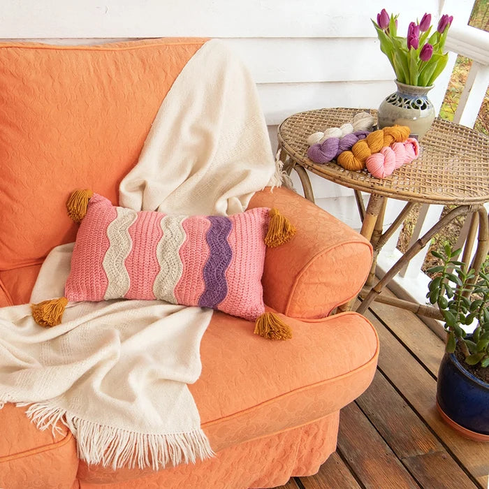 Drifting Away Pillow is a contemporary crochet pillow pattern featuring fun squiggle details and four chunky tassels.