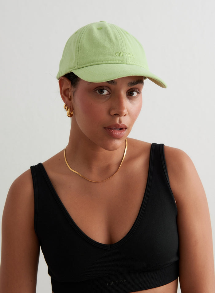 Matcha green cotton Small Logo Cap with embroidered aim'n logo, worn by a woman in a black tank top.