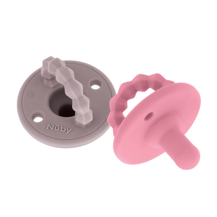 The Nuby Silicone Softees Pacifier & Teether (2 Pack) features one gray and one pink pacifier with round bases and textured handles, shown on a white background—gray lying flat, pink angled to display its nipple.