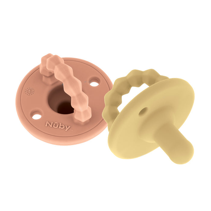 The Nuby Silicone Softees Pacifier & Teether (2 Pack) includes light pink and beige pacifiers, each with a round shield and wavy handle for soothing babies. Specially designed silicone construction offers comfort and safety.