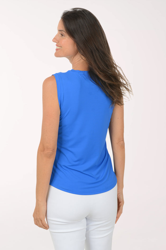 Woman wearing a blue sleeveless top and white pants on a white background
