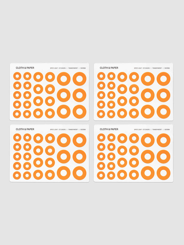 Four sheets of circular stickers of various sizes in a bright orange, arranged on a light gray background.