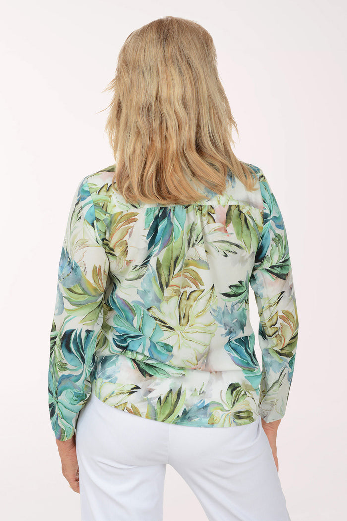 Woman wearing a tropical leaf patterned shirt on a white background