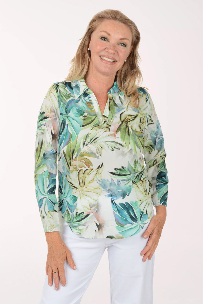 Woman wearing a tropical leaf patterned shirt on a white background