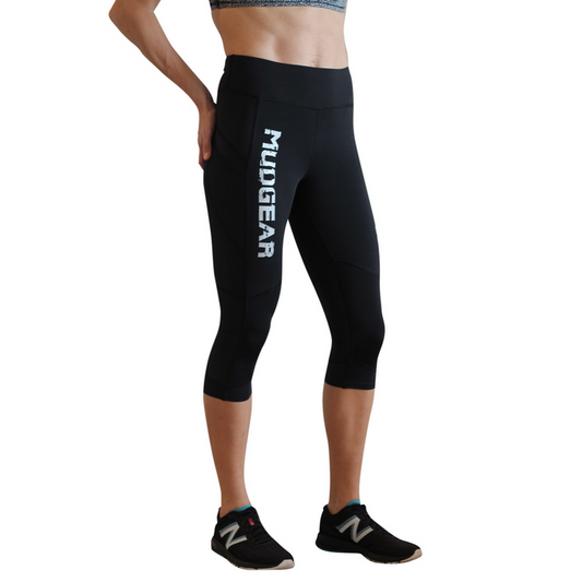Woman wearing black MudGear compression capri leggings with white logo text on thigh